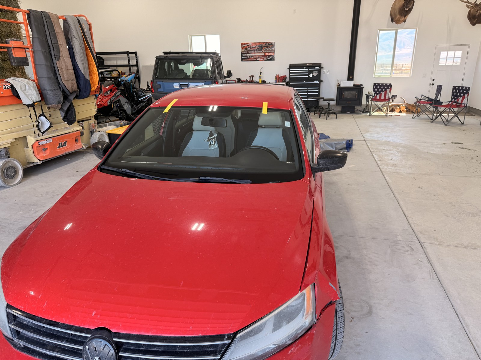 Sedan windshield replaced in the shop bay, taped while the urethane sets.